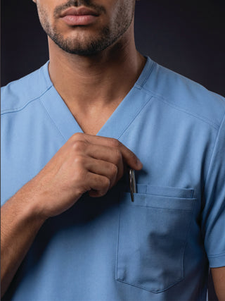 Kyur men's blue scrub top, close-up of chest pocket holding a pen