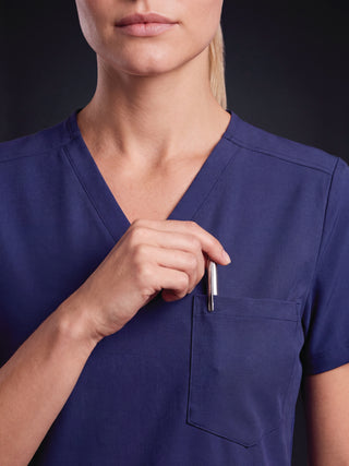 Kyur women's royal blue V-neck scrub top, close-up of chest pocket holding a pen